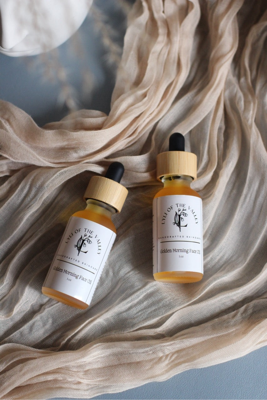 Two bottles of 'Golden Morning' Face Oils on a textured fabric background