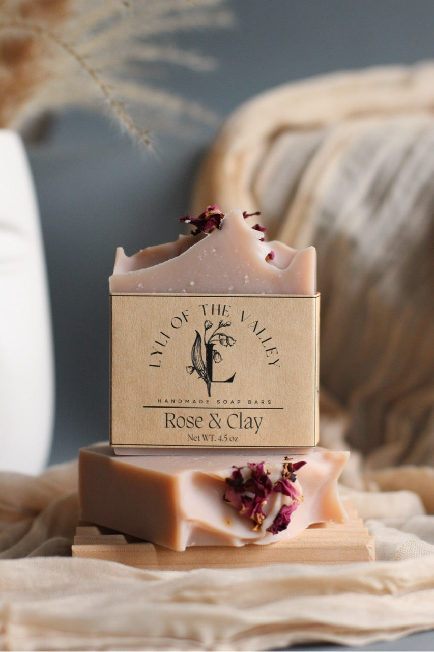 Handmade soap bar with 'Lily of the Valley' branding on a wooden stand.